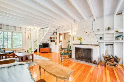a living room with a fireplace and a table at 8 Mi to Mount Snow Rustic Marlboro Cottage in Brattleboro