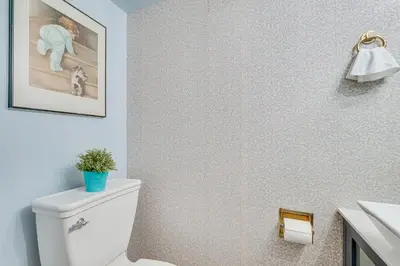 a bathroom with a toilet and a picture on the wall at French-Inspired Townhome 9 Mi to Saratoga Springs! in Malta