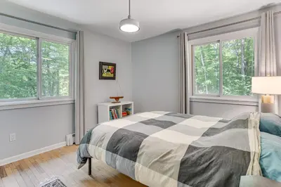 a bedroom with a bed and two windows at Cozy Woodland Home! Ski and Hike Coastal Connecticut in Killingworth