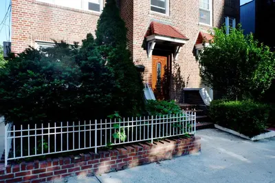 a brick house with a white fence in front of it at Newly Renovated - Minutes from the City in Woodside