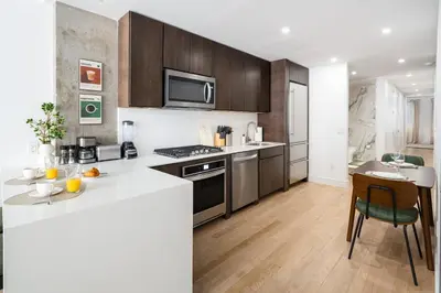 a kitchen with a white counter top and wooden cabinets at Luxury Full Floor Chelsea with WasherDryer 2bd in New York