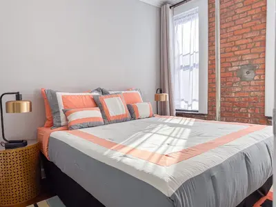 a large bed in a room with a brick wall at New York Suite Upper East Side - Manhattan in New York