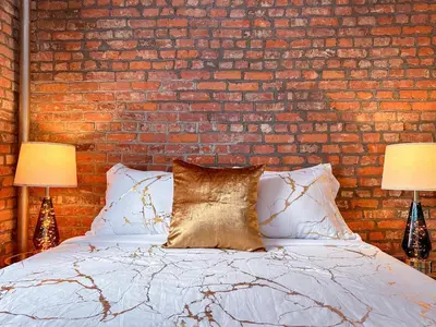 a bedroom with a brick wall and a bed with two lamps at New York Suite Upper East Side - Manhattan in New York
