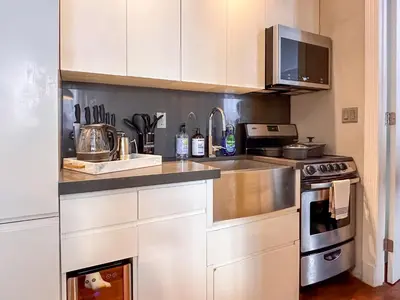 a kitchen with white cabinets and a sink and a stove at New York Suite Upper East Side - Manhattan in New York