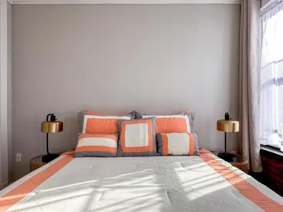 a bedroom with a bed with orange and white pillows at New York Suite Upper East Side - Manhattan in New York