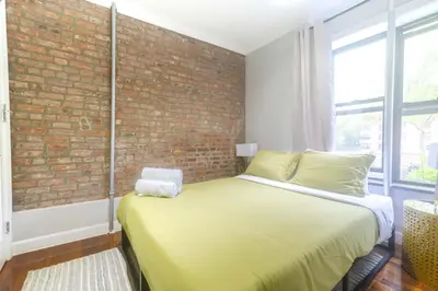 a bed in a room with a brick wall at New York Suite Upper East Side Manhattan in New York