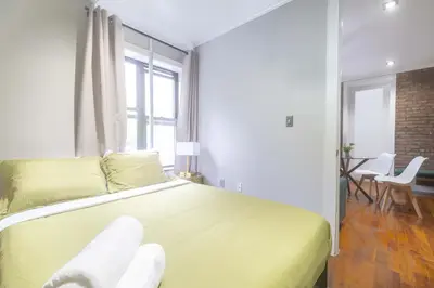 a bedroom with a large yellow bed and a dining room at New York Suite Upper East Side Manhattan in New York