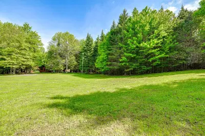 a large grass field with trees in the background at Cardinal Pines Cabin on 8 Acres - Dog Friendly! in New Berlin