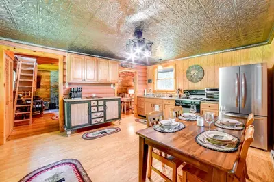 a kitchen with a wooden table and a refrigerator at Cardinal Pines Cabin on 8 Acres - Dog Friendly! in New Berlin