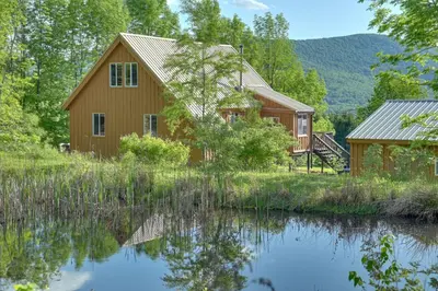a house with a pond in front of it at Catskills Cabin Rental with Hot Tub and Amazing Views! in Stamford