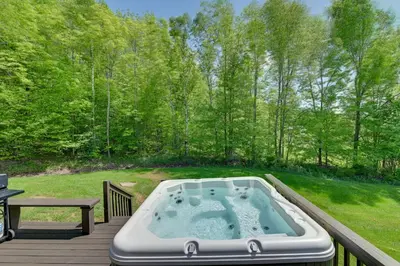 a hot tub on a deck next to a picnic table at Catskills Cabin Rental with Hot Tub and Amazing Views! in Stamford