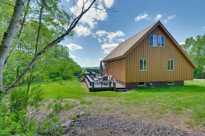 a cabin in the woods with a deck and a house at Catskills Cabin Rental with Hot Tub and Amazing Views! in Stamford