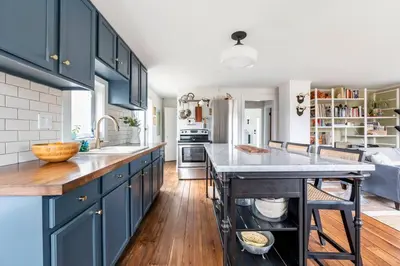 a kitchen with blue cabinets and a large island at Hillcrest Cottage - Charming Cottage with hot tub and view! in Obernburg