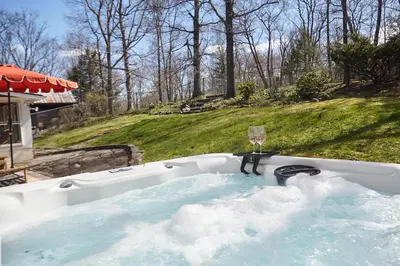 a bath tub with a glass of wine in it at Catskills Retro Retreat- Upstate Home W Hot Tub in Saugerties