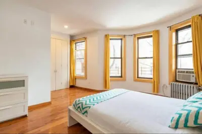 a bedroom with a large bed and some windows at 9Away in The Bronx in Tremont