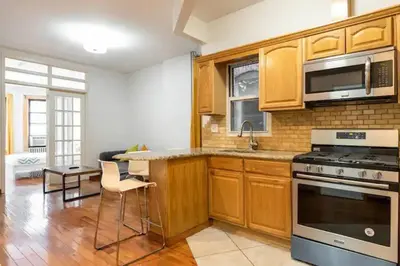 a kitchen with wooden cabinets and a stove top oven at 9Away in The Bronx in Tremont