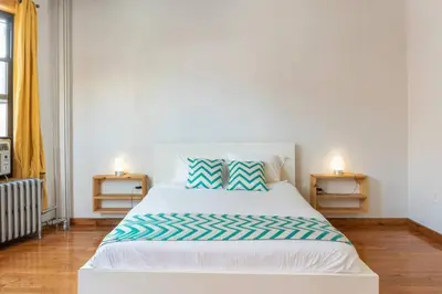 a white bed with blue and white pillows in a bedroom at 9Away in The Bronx in Tremont