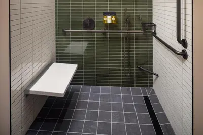a green tiled bathroom with a bench in it at The Heartwood in Poughkeepsie