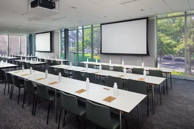 a conference room with tables and chairs and a projection screen at The Heartwood in Poughkeepsie