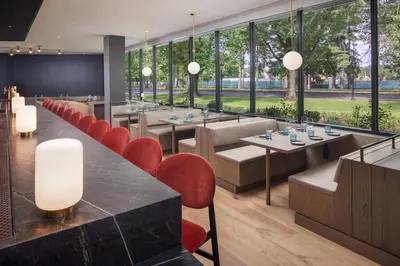 a restaurant with tables and red chairs and large windows at The Heartwood in Poughkeepsie