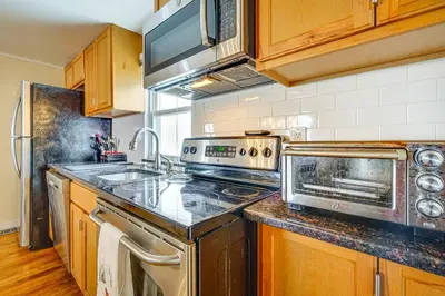 a kitchen with stainless steel appliances and wooden cabinets at Bennington Gem with Smart TV Near Historic District! in Bennington