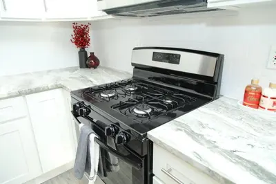 a black stove in a kitchen with white cabinets at Grace Filled Apartment in Newark in Newark