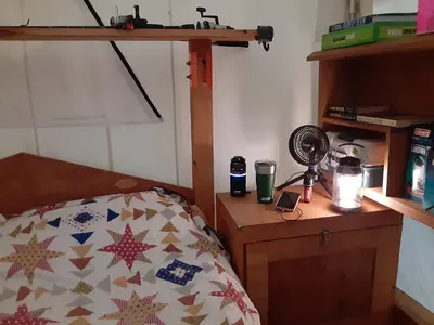 a bedroom with a bed and a wooden nightstand with a bedspread at Riverfront Ritz campsite in Lake Luzerne