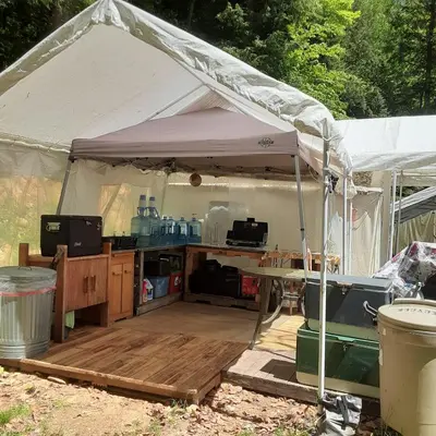 a white tent with a wooden deck under it at Riverfront Ritz campsite in Lake Luzerne