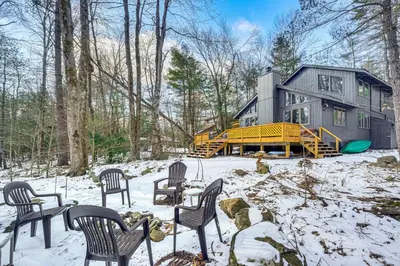 a house in the woods with chairs in the snow at Creek Access and Deck Family Pocono Pines Cottage in Pocono Pines