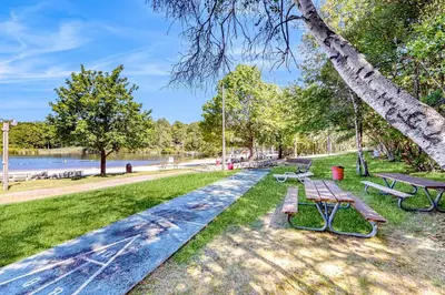 a park with benches and a tree and water at Pocono Waterside Escape in Tobyhanna