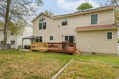 a house with a wooden deck in the yard at Pocono Waterside Escape in Tobyhanna