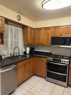 a kitchen with wooden cabinets and a sink and a stove at La Casa Bonita Near NYC in Yonkers