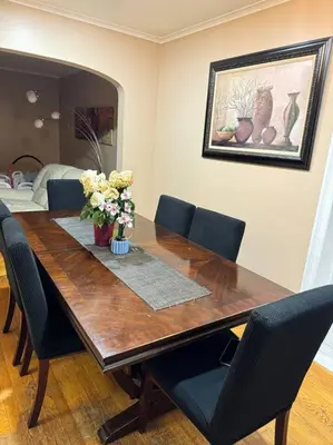 a wooden table with chairs and a vase of flowers on it at La Casa Bonita Near NYC in Yonkers