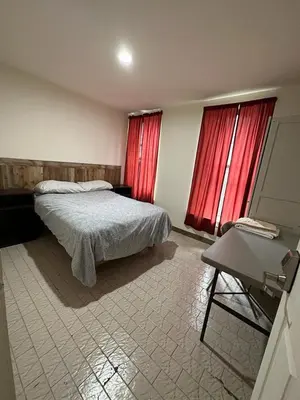 a bedroom with a bed and two windows with red curtains at Hudson Yard 408 in New York