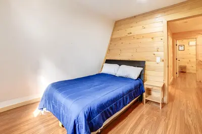 a bedroom with a blue bed and a wooden wall at Creekside Cabin in Bainbridge with Wraparound Deck! in Sidney