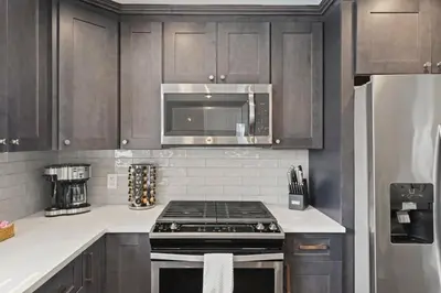 a kitchen with wooden cabinets and a stove top oven at Azure Loft by Saratoga Stays in Saratoga Springs