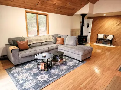 a living room with a couch and a fireplace at Rustic Catskills Cabin with Hot Tub and Mountain Views in Prattsville