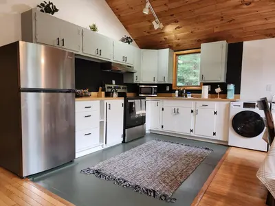 a kitchen with white cabinets and a stainless steel refrigerator at Rustic Catskills Cabin with Hot Tub and Mountain Views in Prattsville