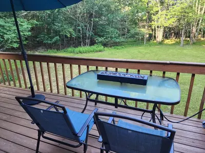 a table and two chairs on a deck with an umbrella at Rustic Catskills Cabin with Hot Tub and Mountain Views in Prattsville