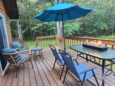 a patio with a table and chairs and an umbrella at Rustic Catskills Cabin with Hot Tub and Mountain Views in Prattsville