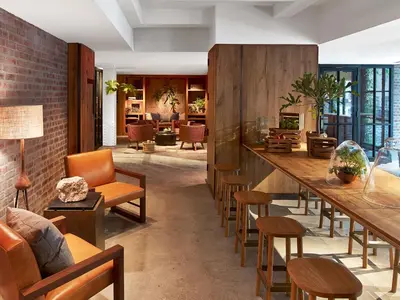 a lobby with a long bar with chairs and tables at 1 Hotel Central Park in New York