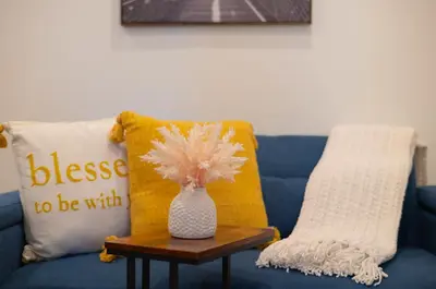 a blue couch with two pillows and a vase on a table at 25 mins to Midtown Manhattan in Guttenberg
