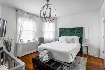 a white bedroom with a large bed and a chandelier at The Fred Deluxe 7 BR by I95 Train HarborVw Beach in Stamford