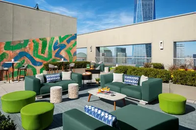 a patio with green couches and tables and a mural at Tribeca 1br w doorman gym roof deck NYC-1374 in New York