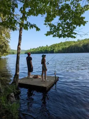 two people fishing on a dock on a lake at Tentrr Riverfront Ritz in Lake Luzerne