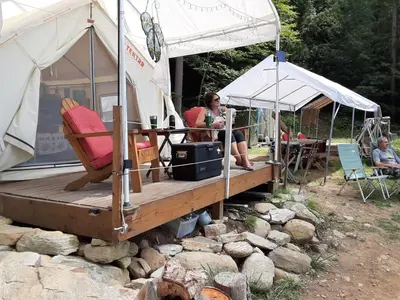a woman sitting on a deck in a tent at Tentrr Riverfront Ritz in Lake Luzerne