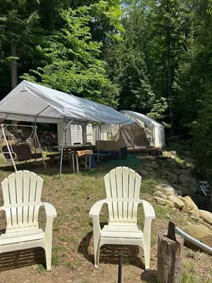 two white chairs in a yard with a tent at Tentrr Riverfront Ritz in Lake Luzerne
