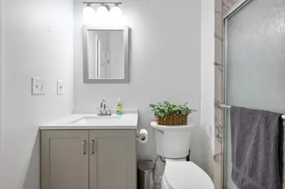 a bathroom with a toilet and a sink and a mirror at Modern Home 4BR 3BA - 20 Min to Timesquare in Jersey City