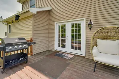 a patio with a grill and a chair next to a house at 1 Mi to Lakes Family Pocono Home with Yard and Deck! in Long Pond
