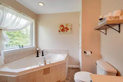 a bathroom with a tub and a toilet and a window at 1 Mi to Lakes Family Pocono Home with Yard and Deck! in Long Pond